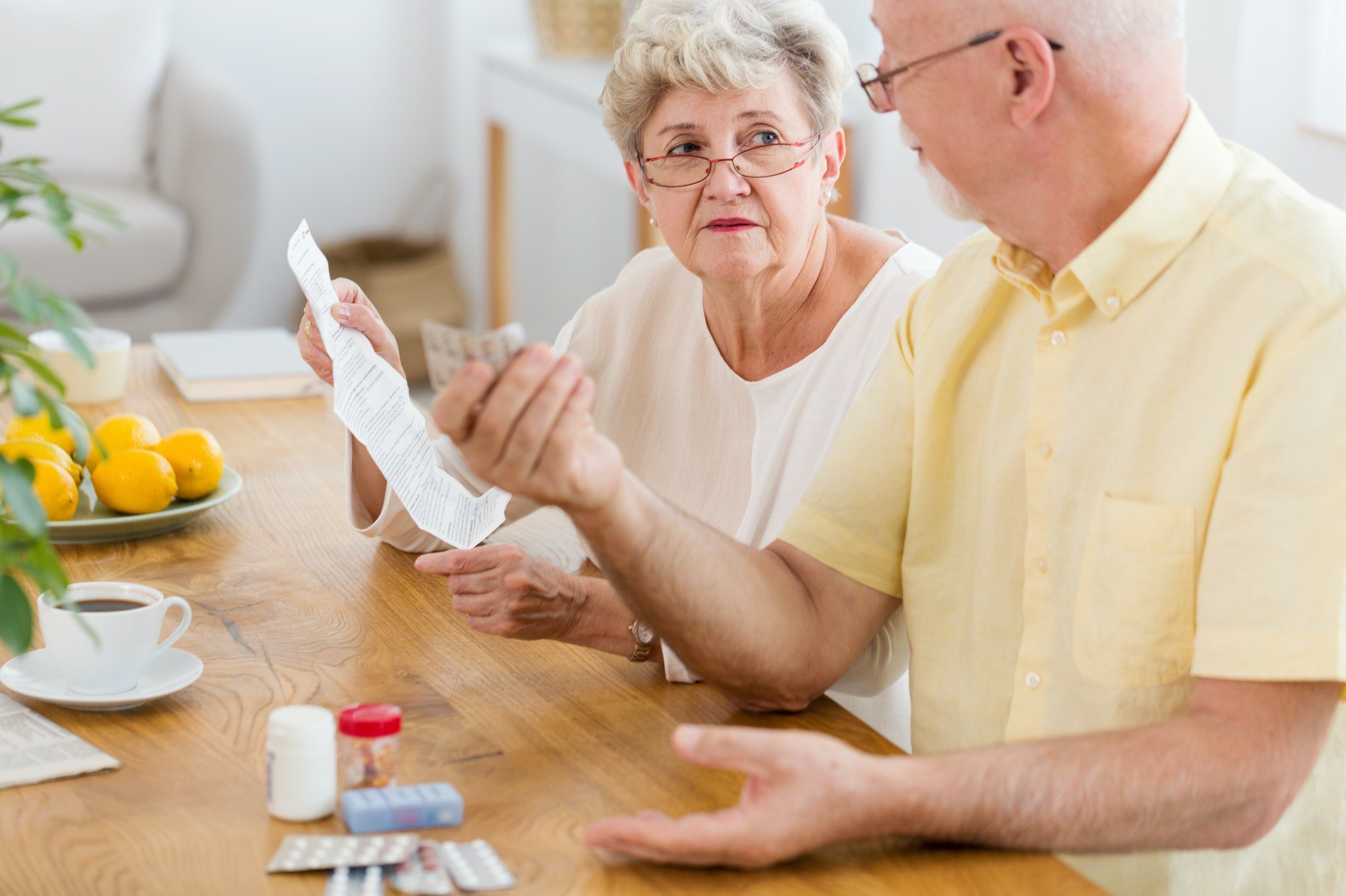 Senior woman reading leaflet of a drug and elderly man holding p
