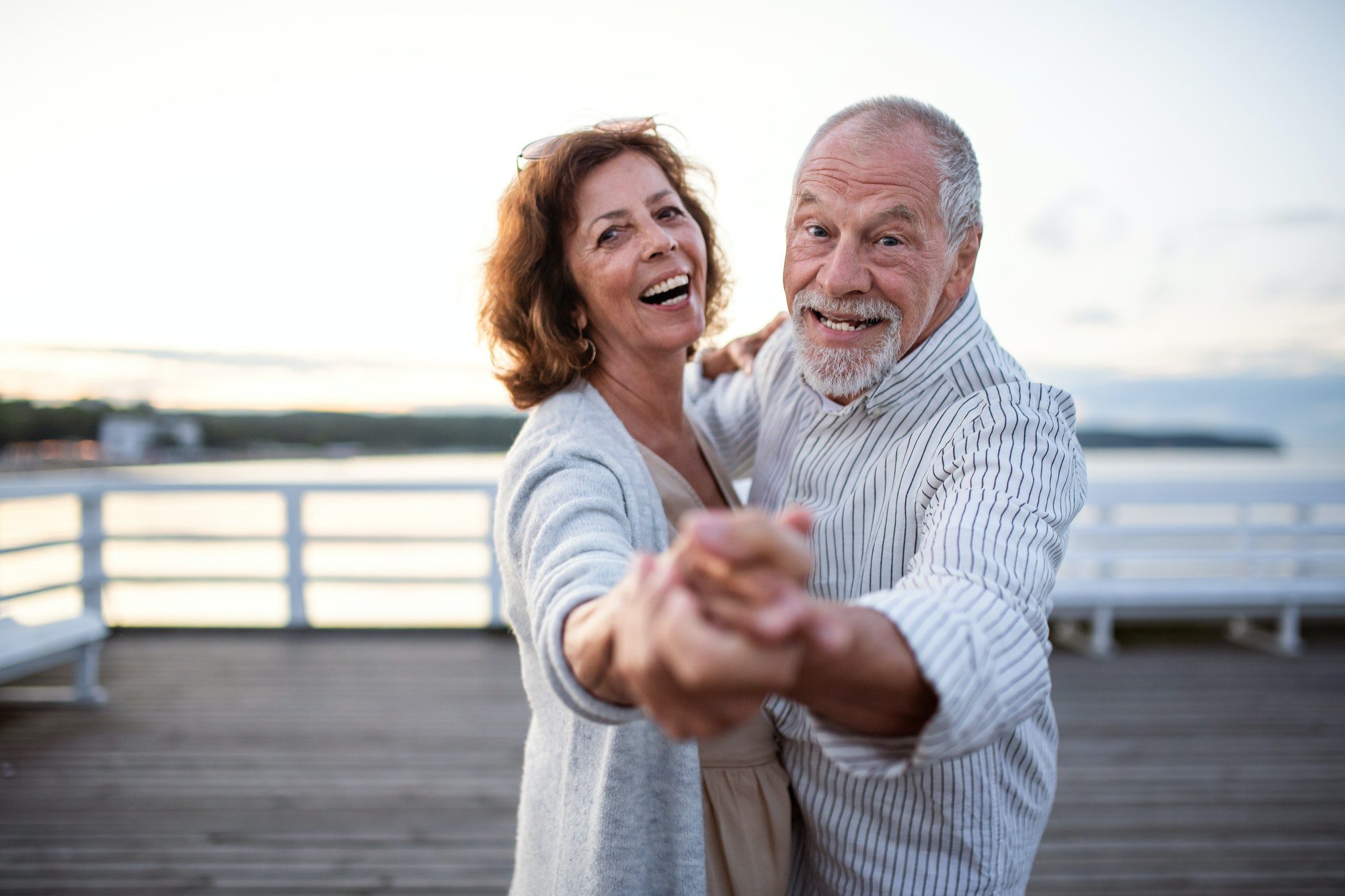 Happy senior couple dancing on a dock as they discuss medicare options in Booneville, Mississippi.