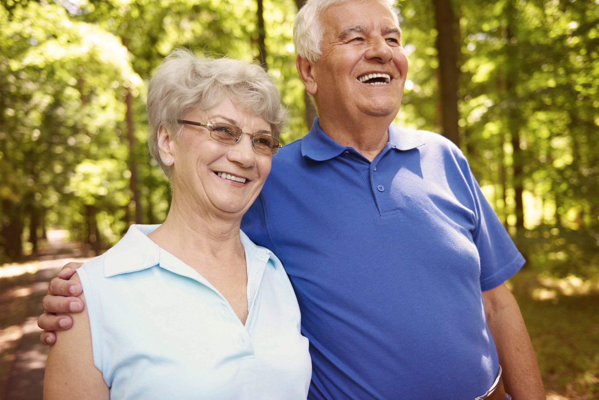 Happy couple enjoying walk in the woods as they discuss Medicare Supplement open enrollment.